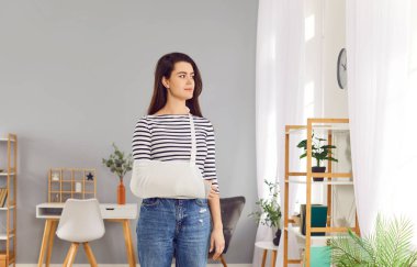 Yaralanma, yaralanma, dirsek kemiği ağrısı, koruyucu bandaj, travma rehabilitasyonu, sağlık sigortası, tedavi sonrası rehabilitasyonda kırık kol askısı takan genç bir kadın.