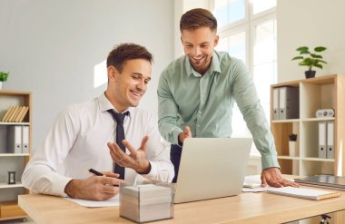 İki güveni tam iş adamı iş yerinde dizüstü bilgisayar ekranına bakıp toplantıda şirket finansmanını tartışıyor. Ofiste çalışan çalışanlar ve erkek çalışanlar.