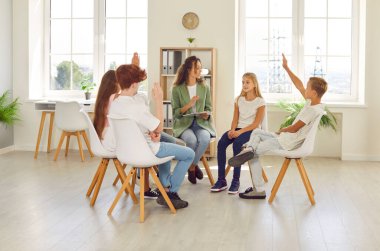 Bir grup okul çocuğu ve bir öğretmen okulda bir çember içinde oturuyorlar. Ders sırasında çocuklar bir soruya cevap vermek için ellerini kaldırırlar. İlköğretim okulu, çember zamanı, psikologla seanslar.