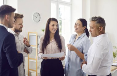 Bir grup ofis çalışanı iş yerlerinde dikilip iletişim kuruyor, yakın çekimde. Takımda bölünme kavramı. Bir tartışmadaki bir adam çoğunluğun görüşüne katılmaz, tuhaflık...