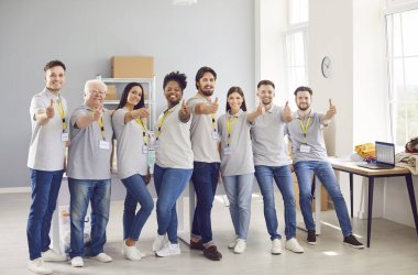 Çok ırklı mutlu gönüllülerden oluşan bir ekip, bir insani yardım merkezinde onay veriyor. İnsanlar gülümsüyor ve jestler kendilerini hayır işlerine, hizmete, toplum yardımına ve bağışına adadıklarını yansıtıyor.