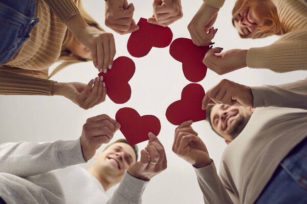 Heart red paper symbol, group circle celebrating Saint Valentine party together. Молодежное общество, клуб друзей Валентина тематическое мероприятие, романтические партнеры держащие карты, чтобы играть, наслаждаться романтическим вечером свидания 