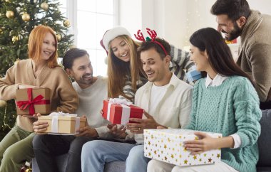 Yeni yıl partin kutlu olsun, mutlu noel kutlaması arkadaşların hediyeleri açıyorlar birlikte kutluyorlar, heyecanlı insanlar eğleniyorlar şenlik ağacının yanında birlikte eğleniyorlar. 