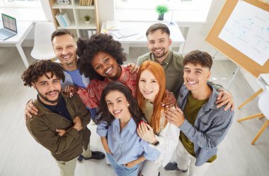 Muhtelif, çok uluslu bir iş ekibinin grup portresi ofiste bir arada duruyor. Mutlu bir grup insan, profesyonel bir ortam içinde bir topluluk ve işbirliği duygusu sergiliyor..