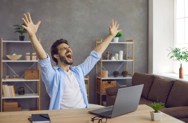 Çalışma masasında dizüstü bilgisayarla oturan adam heyecanlanıyor, ellerini kaldırıyor ve çığlık atıyor. Mutlu adam iş projesini bitirir, iyi haberler öğrenir, üniversite ya da üniversite bursu kazanır.