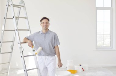 Tadilat ya da inşaat sırasında profesyonel bir erkek ressamın portresi. Becerikli adam uzmanlığı ve çalışmaya olan bağlılığı, evi dönüştürme ve projenin genel başarısına katkıda bulunma.