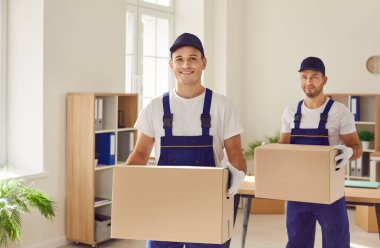 İki adamın portresi, bir nakil şirketinin bir parçası, bir ofiste ya da evde duruyor. Kutular elindeyken, nakliyeci profesyonellik sergiliyor, birinci sınıf teslimat ve nakliye hizmetleri sunmaya hazır..