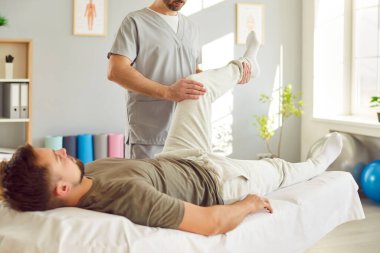 Erkek fizyoterapist rehabilitasyon kliniğinde dizinde tedavi görüyor. Ofiste çalışan profesyonel fizyoterapist ya da osteopat. Fizyoterapi ve osteopatik tıp konsepti.