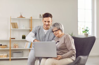 Gülümseyen doktor ya da hemşire yaşlı bir kadına teknolojide yardım ediyor. Bakıcı ona internet dünyasında dizüstü bilgisayar kullanarak rehberlik ediyor. Yaşlılar için dijital bölünmenin köprülenmesi.