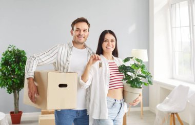 Yeni taşınan, mutlu, gülen aile anahtarı olan, daire alan, kutucuğu eşyalarla birlikte taşımayı kutlayan, eğlenen, taşınmanın keyfini çıkaran, paketleme hayalleri kuran, dekorasyon yapan bir çift. 