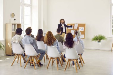 Şirketin istatistiklerini ve finansal verilerini diyagram ve grafiklerle gösteren genç çekici adam konferansta toplantıda büyümeyi analiz eden ya da iş eğitimi alan izleyicilere.