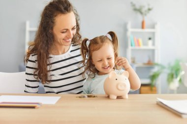 Anne ve çocuk birlikte para biriktirip evdeki domuz kumbarasına para koyuyorlar. Bu aile aktivitesi zenginlik, kar ve sorumluluk değerlerini teşvik ederek anlamlı paylaşımlı deneyimler yaratıyor..