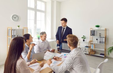 Ofisteki iş adamlarına koçluk, ofiste mali eğitim atölyesi sunumu, profesyonel koçu dinleyen çalışanlar, strateji geliştiren iş arkadaşları, takım çalışması