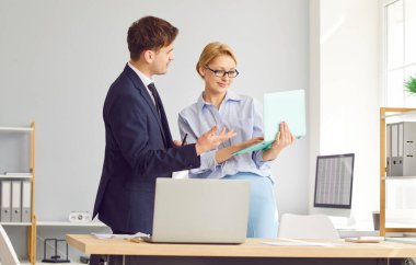 Ofiste çalışan iki kişi. Meslektaşı ile birlikte dizüstü bilgisayar kullanan bir muhasebeci. Genç bir adam ve kadın bir ofis masasının başında dizüstü bilgisayardaki bir belgeye bakıyorlar.