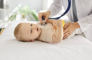Sağlık kontrolü sırasında kalp atışlarını dinleyen bir kadın çocuk doktoruyla birlikte küçük bebek bebek kanepesinde yatıyor. Annelik ve bebek sağlığı kavramı.
