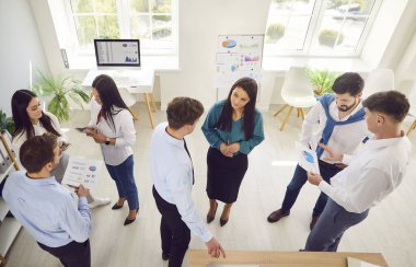 Bir grup kendine güvenen iş adamı erkek ve kadın bir toplantı sırasında ofiste konuşuyor. Şirket çalışanları içeride çalışıyor, iş ve iş projelerini tartışıyor. Takım çalışması konsepti.