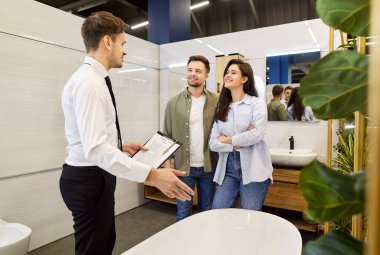Satış elemanı aile tüketicilerine seçmede yardım ediyor, lavabo kabı alıyor, gerekli ev tesisat malzemelerini alıyor, pazarda harika seçimler yapıyor, mutfaktaki müşterilere danışmanlık yapıyor, banyo aksesuarları alıyor.