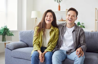 Mutlu, evli bir çiftin neşeli portresi. Rahat bir evde, kanepede kucaklaşıp birlikte gülüyorlar. Tutku, birliktelik ve ilişkilerinde paylaştıkları mutluluk..