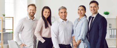 Ofis ortamında birlikte çalışan farklı iş adamlarının grup portresi. Takım çalışması, işbirliği ve profesyonel ortamdaki iş arkadaşları arasındaki olumlu atmosfer.