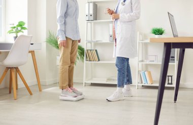 Hastanedeki doktor ya da hemşire muayenesi sırasında hasta tartılıyor. Diyetisyen uygun sağlık yönetimi ve tedaviyi sağlamak için hastanın ağırlığını kontrol eder.