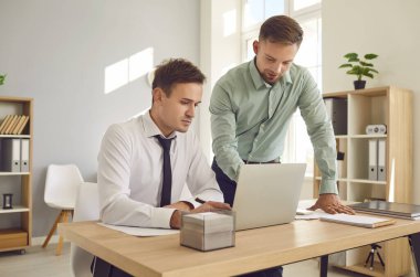 Ofiste birlikte çalışan iki erkek iş arkadaşı, muhasebe işi için dizüstü bilgisayar kullanıyorlar ve iş görüşmesi sırasında konuşuyorlar. İş ortamında işbirliği, iş arkadaşları arasında iletişim.