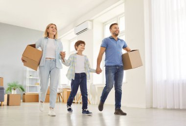 Taşındıkları gün yeni evlerinde paketsiz kutularla gülümseyen küçük çocuklu mutlu bir aile. Ev sahipleri daire almaktan zevk alıyor. Taşınma, emlak, ipotek konsepti.