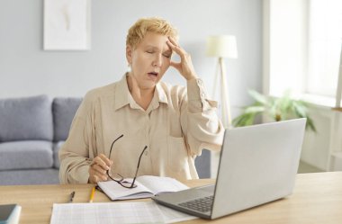 Olgun, mutsuz, serbest çalışan, gözlüklü, üzgün, evde çalışan, bilgisayarda yazan, internetten alışveriş yapan, online sorunu düşünen, düşünceli, düşünceli, kafası karışık bir iş kadını.