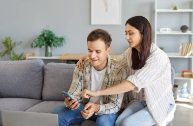 Aile çifti, evde eğlenmek ve sohbet etmek için akıllı telefon kullanıyor. Birlikte interneti keşfederler, evlerinde bir bağ ve rahatlama anını kucaklarlar..