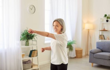 Kıdemli kadın evde dövüş sanatları eğitimi alıyor. Güç ve disipline odaklanıyor. Dinamik egzersiz kişisel spor ortamında spor ve spora bağlılığı gösteriyor.