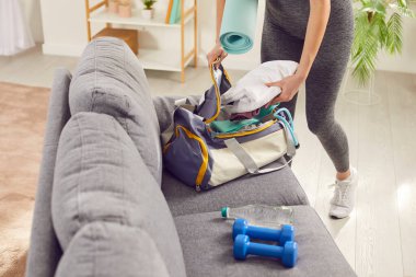 Kadın spor çantasıyla ekipman ve spor kıyafetlerini spor salonunda çalışmak için evde topluyor. Antrenmana hazırlanıyor. Formda kalmak için gereken her şeye sahip olduğundan emin oluyor..