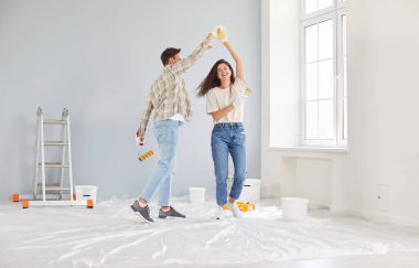 Neşeli aile çifti evlerini yenilerken, duvarları boyarken ve inşaatın keyfini çıkarırken. Yeni bir alan yaratmada kaydedilen ilerlemeyi kutlarken mutluluk bariz bir şekilde görülür..