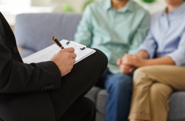 Aile terapisi sırasında bir psikoloğun ellerini yakalar. Danışmanlık ve destek sağlanması, akıl sağlığı alanında oluşan şefkatli bağlantıyı sembolize eder..