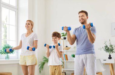 Sporty happy active young family doing morning training, beautiful sporty healthy people, enjoy fitness exercises with dumbbells, workout at home, doing weight training, friendly parent and small kid clipart