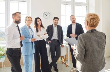 Çeşitli şirket çalışanlarının önünde duran işletme lideri ya da koçun arka planı. Meslektaşlardan oluşan bir ekip, iş toplantısı ya da eğitim süresince bayan meslektaşlarını dinliyor..