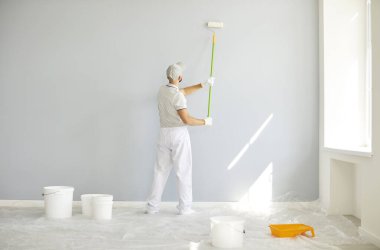 Bina müteahhitinin beyaz elbiseli, elinde boya silindiriyle boş odada fotokopi alanı olan gri duvarı boyadığını gördüm. Erkek ressam apartman onarımı ve tadilat yapıyor..