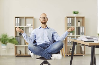 Sakin ofis çalışanı Lotus 'ta koltukta oturmuş yoga yaparken rahatlıyor, stresi azaltmak için meditasyon yapıyor, rahatlama yorgunluğu çekiyor, iş yerinde denge kuruyor, akıl sağlığını geliştiriyor,