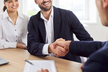 Emlakçı ya da emlakçı bir çiftle el sıkışıyor. Yeni ev, ev ya da mülk için anlaşma imzalıyor. Gayrimenkul alım veya kiralama sürecinde anlaşma ve memnuniyet.