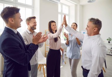 Bir grup pozitif iş adamı birbirlerine beşlik çakıyor, ofiste başarıyı, anlaşmayı ve takım çalışmasını kutluyorlar. Takım birleşmiş ve motive olmuş, birlikte hedeflere ulaşıyorlar..