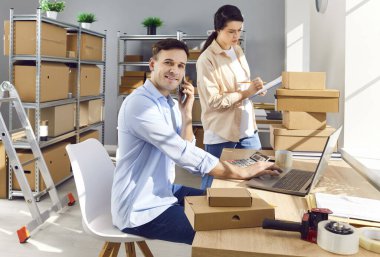 E ticaret deposunda çalışıyorum. Malzeme deposundaki masada oturan erkek yönetici müşteriyi arar, dizüstü bilgisayar kullanır, kadın konsültasyon kontrol listesi göndermeden önce iletişim bilgilerini kontrol eder