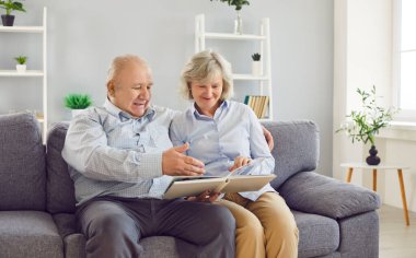 Mutlu, yaşlı bir çiftin portresi. Evdeki oturma odasındaki kanepede oturup aile fotoğrafı albümüne bakıyorlar. Olgun evli erkek ve kadın birlikte vakit geçirmenin tadını çıkarıyorlar..