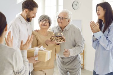 Yaşlı baba ve çocuklar yaşlı anne doğum gününü ya da yıldönümünü evde pasta ve hediyelerle kutluyorlar. Aile mutlu ve birlikte bir partiden zevk alıyor, neşeli anılar yaratıyor..