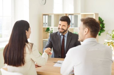 Mutlu çift sözleşme imzalıyor ve simsar ya da sigortacıyla el sıkışıyor. Genç bir adam ve kadın, yatırım danışmanlarıyla iyi bir anlaşma yapıyor..