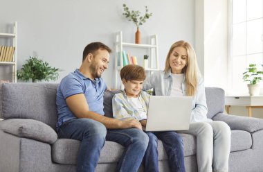 Çocuklu aile, internette eğlence ve iletişim için dizüstü bilgisayar kullanarak evde vakit geçirmeyi seviyor. Bu mutlu, rahat an, paylaşılan internet aktiviteleri aracılığıyla bağlantıyı teşvik eder..