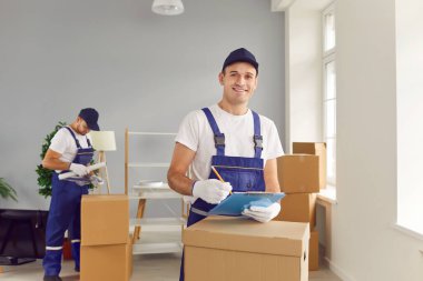 Yeni apartman dairesinde karton kutu teslimatında çalışan mutlu, genç ve profesyonel işçi takımı. Taşınma, taşınma günü ve taşınma konsepti.