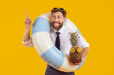 Tişörtlü, kravatlı, mavi beyaz plaj yüzüklü ve gözlüklü mutlu işadamı şirket çalışanı. Yaz tatili tatil beldesinde yukarı bakan turuncu sarı arka planda.