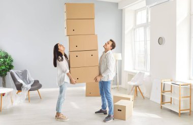 Genç bir aile, karı koca ellerinde karton kutular, yeni bir daireye taşınmak için heyecanlı, mutlu çift eğleniyor, ilk eve taşınmak iyi hissettiriyor, kiralık kiracılar toplanıyor.