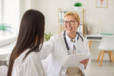 Başhekim ya da hemşire, klinikteki tıbbi bir randevu sırasında hastayla iletişim kurar, destek, sağlık yardımı ve profesyonel bir diyalog kurar..