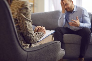 Genç bir adam psikoloğun önünde ağlıyor, yakın plan. Psikolojik yardım kavramı, duygusal zorluklar, derin hayal kırıklığı ve keder. Aile sorunları, depresyon ve stres