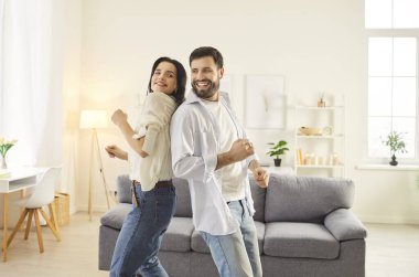 Neşeli, genç bir çift boş zamanın tadını çıkarıyor, rahat oturma odasında arka arkaya müzik eşliğinde dans ediyorlar. Gülümseyen karı koca özel anı kutluyor ve rahatlatıcı hafta sonlarında birlikte eğleniyorlar..