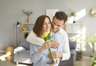 Sevgi dolu koca karısına nazikçe sarılıyor, Uluslararası Kadınlar Günü 'yle, doğum günüyle ya da bir buket laleyle tebrik ediyor. Mutlu çift evde romantik bir olay kutluyor..